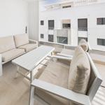Terrace with white sofa, table, and seating. View of modern buildings.