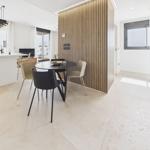 Dining area with round table and chairs next to kitchen island and wood panel.