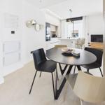 Dining area with round table and chairs. Kitchen and living area are visible.