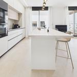 Modern kitchen with island, built-in oven, and large window view.