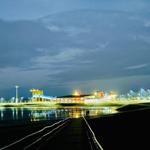 Nachtansicht eines beleuchteten Hafens mit Pier und Reflexionen im Wasser.