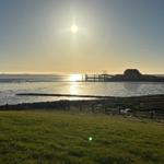 Sonnenuntergang über Watt und Wasser, mit Haus und Steg im Hintergrund.