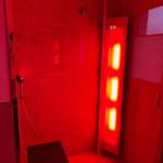 Dusche mit roter Beleuchtung und Sitzbank