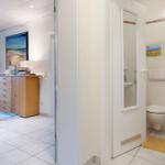 Badezimmer mit Toilette und Spiegel. Nebenraum mit Schrank und Wandbild.