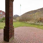 Hinterhof mit Steinplatten, Blick auf grünen Rasen und Hang.