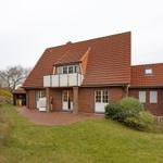 Rotes Ziegelhaus mit Balkon und Garten. Eingangsbereich mit weißen Türen.
