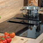 Küchenherd mit Topf, Tomaten und Basilikum auf Holzoberfläche