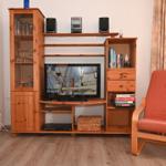 Ein Raum mit Holzmöbeln, Fernseher, Stuhl und Bücherregal.