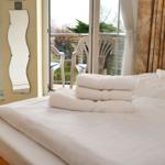 Schlafzimmer mit Bett, Handtüchern und Blick auf Balkon mit Stühlen.