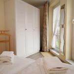 Schlafzimmer mit Doppelbett, Kleiderschrank und Fenster zur Terrasse.