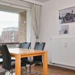 Esszimmer mit Holztisch, schwarzen Stühlen und Blick auf Balkon. Wand mit Seehund-Fotos.