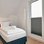 Schlafzimmer mit Bett, Nachttisch und Fenster mit Jalousie.