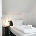 Ein Schlafzimmer mit einem Bett, einer Nachttischlampe und gefalteten Handtüchern.