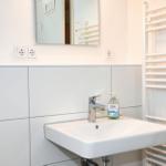 Waschbecken mit Spiegel und Handtuchhalter in weißer Wand