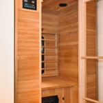 Innere Ansicht einer Holzsauna mit Sitzbank und Steuerungselementen an der Wand.