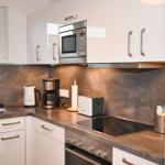 Küche mit weißen Schränken, Edelstahlgeräten und dunkler Arbeitsplatte.