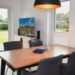 Esstisch mit Stühlen, Fernseher und Fenster zur Terrasse.