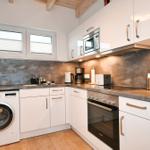 Küche mit Waschmaschine, Herd, Mikrowelle und Fenster.