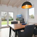 Esszimmer mit Esstisch, Stühlen, TV und Kaminofen. Durchgangstür zum Garten.