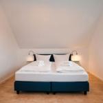 Schlafzimmer mit Doppelbett, Fenster und Wandlampen.