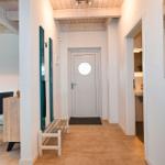 Hausgang mit Tür, Bad und Essbereich mit Tisch und Stühlen.