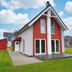 Moderne Villa mit roten und weißen Außenwänden, großem Holzdeck und grünem Rasen.