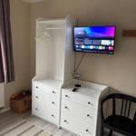Schlafzimmer mit Kleiderschrank, Fernseher und Stuhl. Spielzeugkiste neben Fenster.