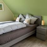 Schlafzimmer mit Bett, Nachttisch und grüner Wand