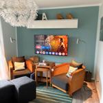 Wohnzimmer mit zwei Sesseln, Fernseher und Deckenleuchte.