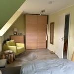 Schlafzimmer mit Bett, Schrank und Sessel unter Dachschrägen.