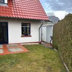 Haus mit rotem Dach, weißer Fassade und Gartenbereich mit Rasenfläche.