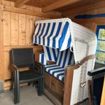 Hochwertige Strandkörbe mit blau-weißem Stoff in Holzhaus. Neben einem Stuhl.
