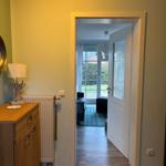 Hausgang mit Holzschrank, Heizkörper und Blick in Wohnbereich mit Fenster.