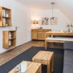 Wohnzimmer mit Holzmöbeln, Sofa, Esstisch und Wandregalen unter Dachschräge.