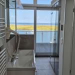 Badezimmer mit Dusche und Blick auf Wasser und Strand