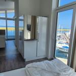 Schlafzimmer mit Blick auf Hafen und Meer. Neben dem Bett befindet sich ein Flur mit Bad.