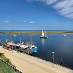 Hafen mit Booten und Blick auf die Insel unter blauem Himmel.