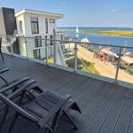 Terrasse mit Sitzgelegenheiten und Blick auf Hafen und Wasser.