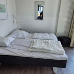 Schlafzimmer mit Bett, Spiegel und Fenster zur Aussicht.