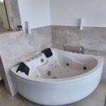 Bad mit Whirlpool, Waschbecken und Blick auf Balkon.