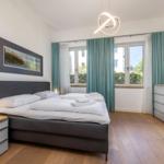 Schlafzimmer mit Bett, TV und Fenster mit Blick auf Balkon.