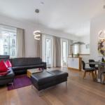 Wohn- und Essbereich mit Sofa, Esstisch und Fenstern.