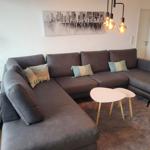 Ein großes L-Förmiges Sofa mit Kissen, zwei runde Tische und eine Wanddekoration.