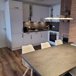 Küche mit Essbereich, weiße Schränke, Backofen und Backsteinwand.