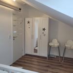 Schlafzimmer mit Kleiderschrank, Hochstuhl und Holzboden unter Dachschrägen.