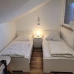 Zwei Einzelbetten mit Nachttisch und Lampe unter Dachschrägen.