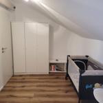 Kammer mit Babybett, Kleiderschrank und Holzboden unter Dachschrägen.