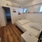 Schlafzimmer mit Bett, Kleiderschrank und Fenster. Tür führt in Bad.