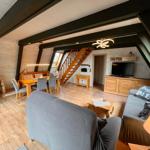 Wohn- und Essbereich mit Holzdielen, Sofa, Tisch und Stühlen sowie Treppenhaus.