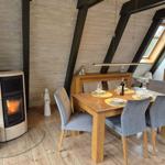 Esszimmer mit Esstisch, Stühlen und Kaminofen unter Holzdecke.